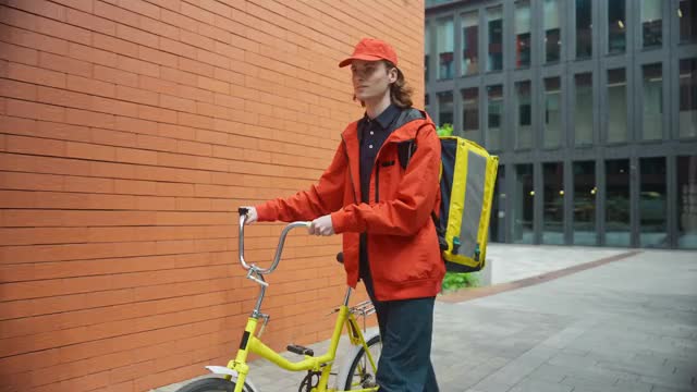 オフィス街を自転車を押して歩くフードデリバリーの男性の動画｜無料の動画素材サイト